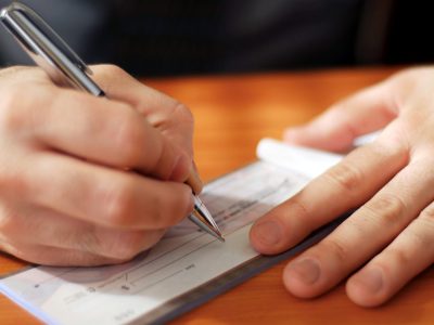 Closeup on man`s hands writing a check